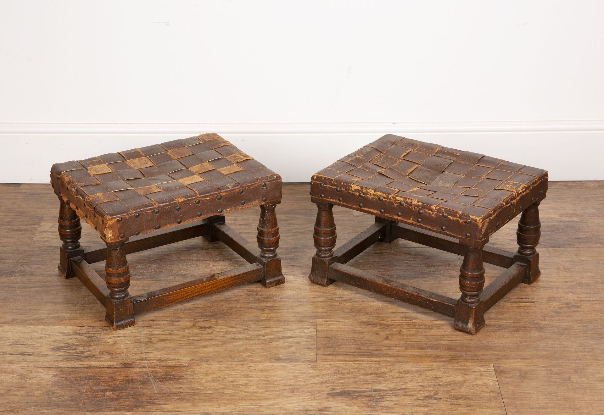 Arts and Crafts near pair of oak framed footstools with woven leather tops, in the manner of
