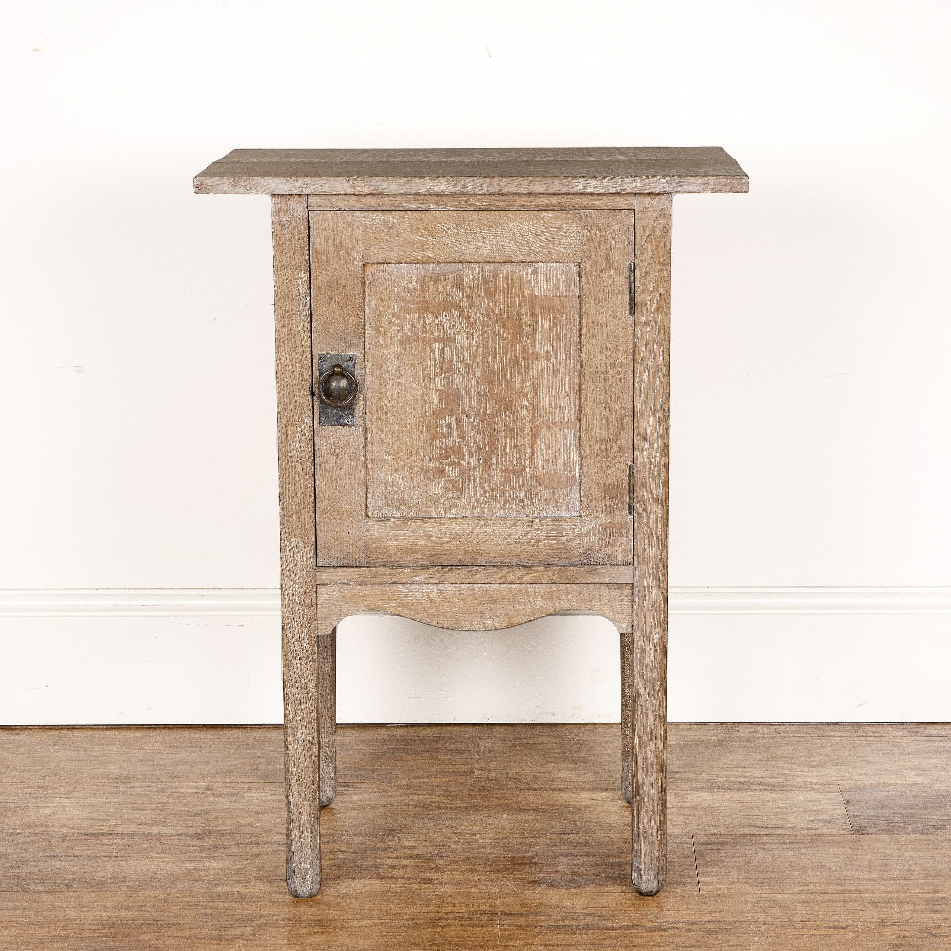 In the manner of Heals limed oak, side cupboard, with overhead top and the door with brass ring