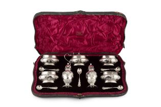 A late Victorian silver seven piece cruet set, with gadrooned borders and embossed with ribbon