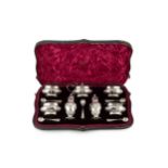 A late Victorian silver seven piece cruet set, with gadrooned borders and embossed with ribbon