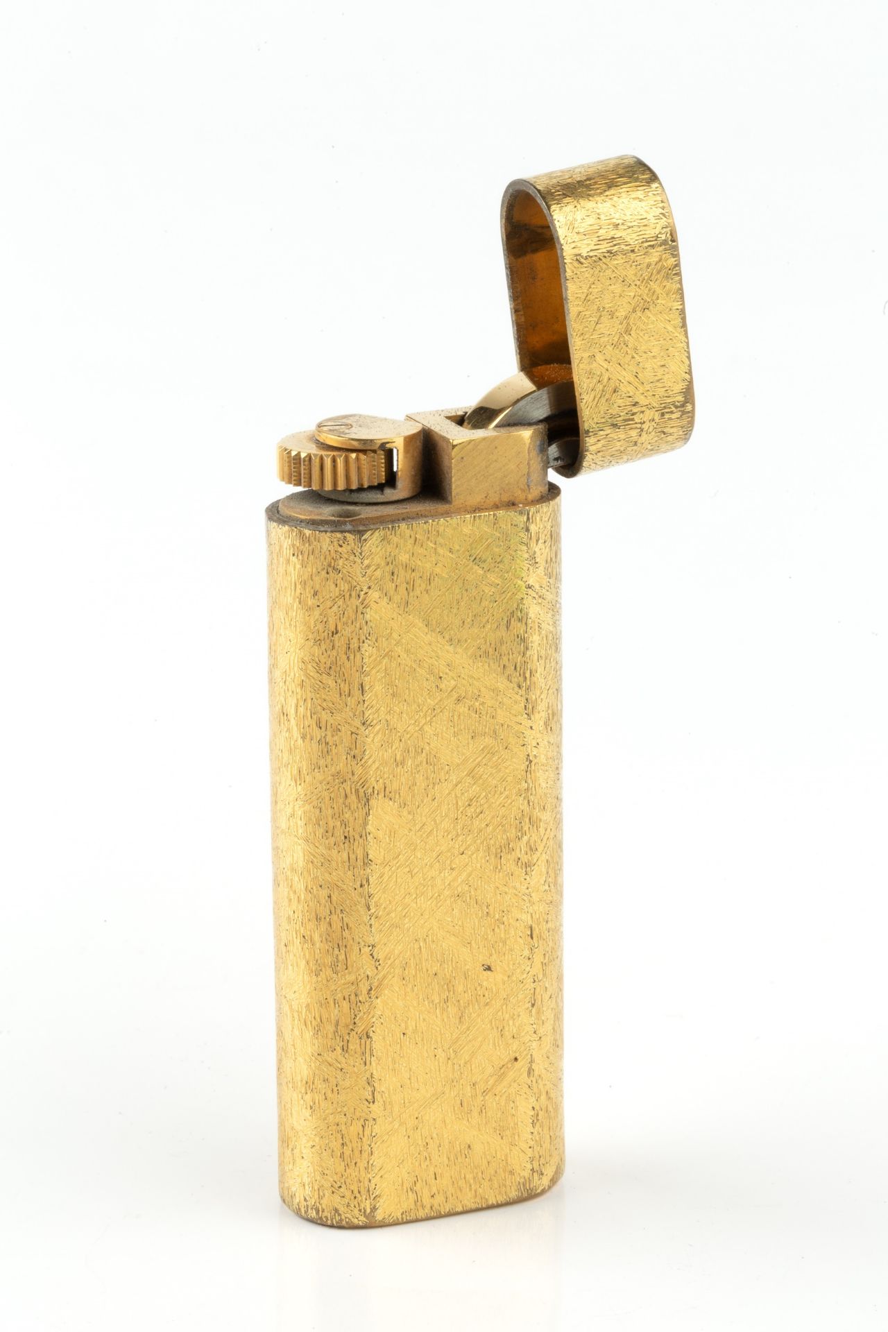 A gold plated lighter by Cartier, of rounded rectangular form and having textured decoration, no.