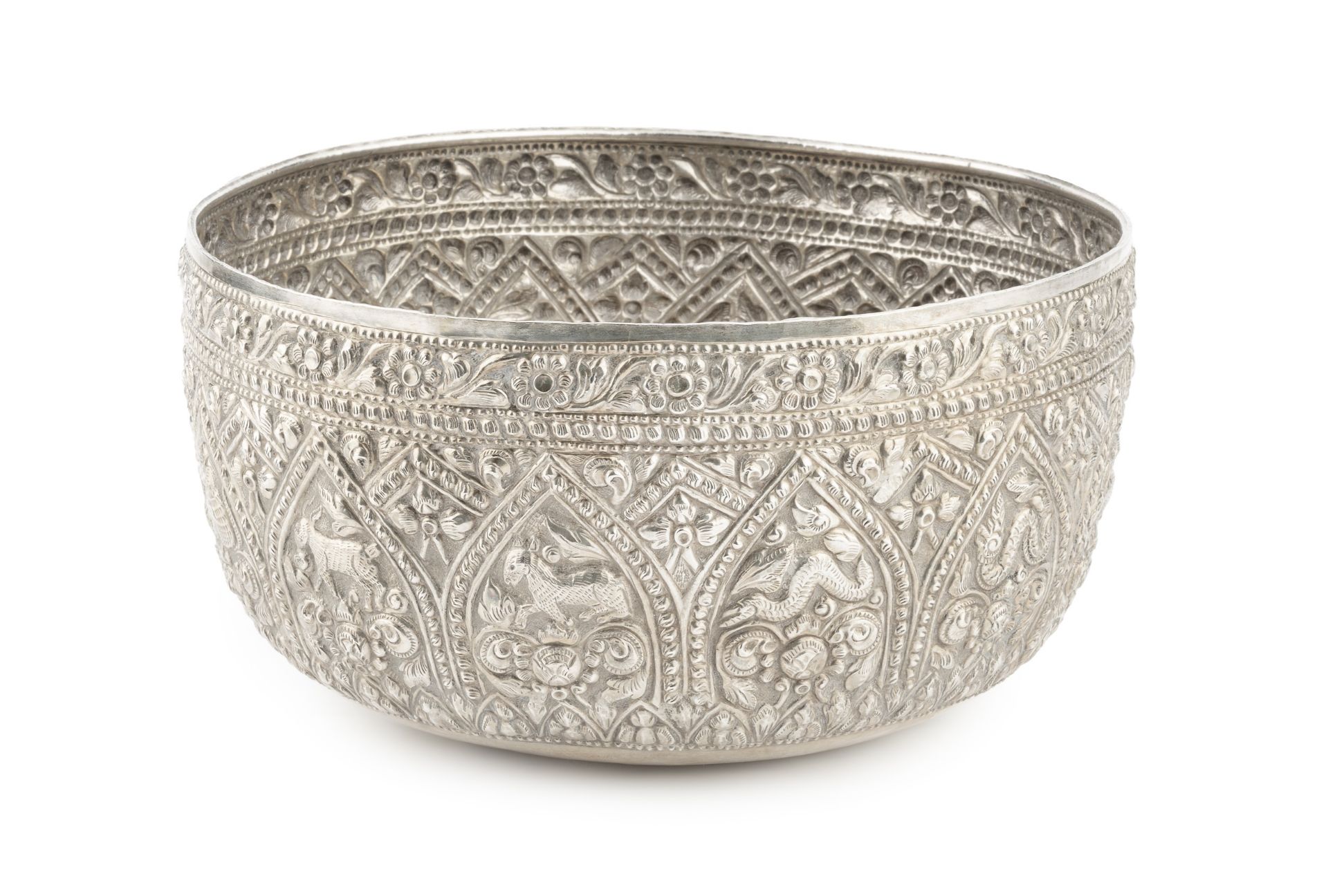 A Burmese white metal thabeik bowl, embossed and engraved with numerous animals and stylised foliage