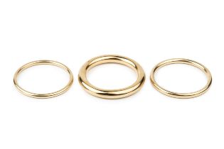 A 9ct gold hollow circular bangle, of plain design, stamped 375, 7.8cm wide, and two further similar