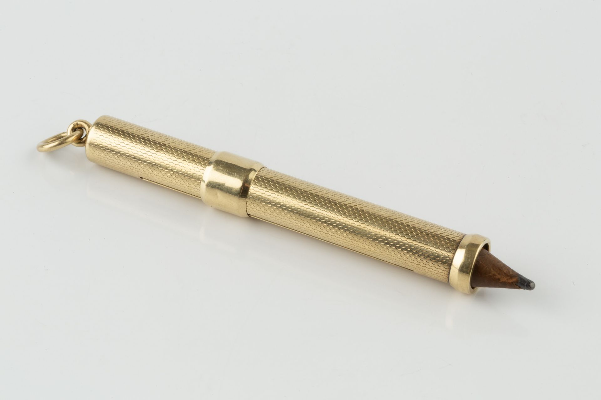A gold propelling pencil, with engine turned decoration, the suspension ring stamped 585, 7.5cm - Bild 2 aus 2