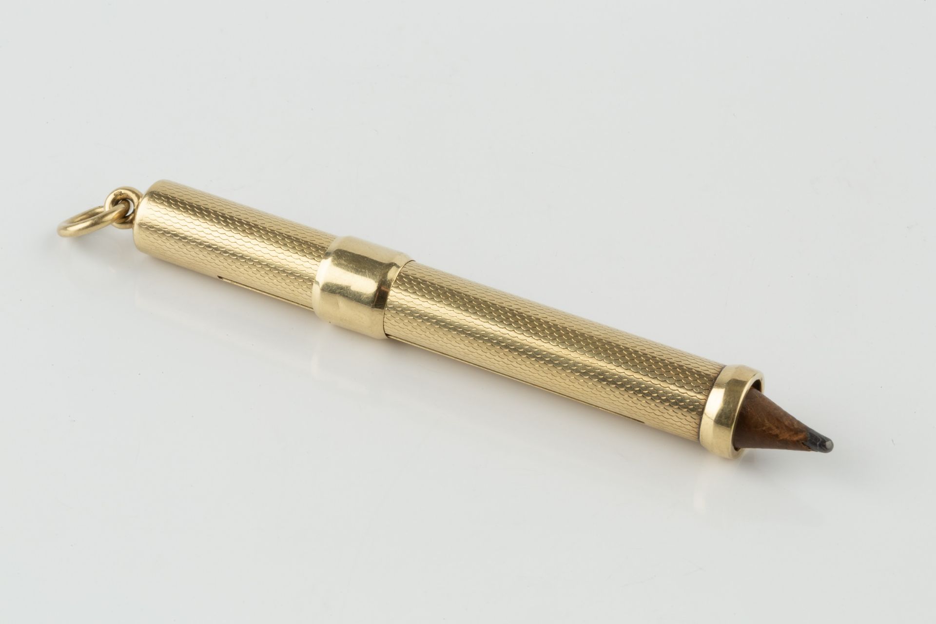 A gold propelling pencil, with engine turned decoration, the suspension ring stamped 585, 7.5cm - Image 2 of 2