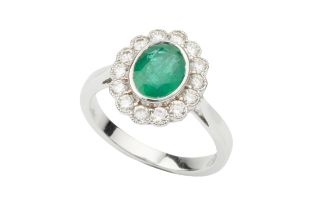 An emerald and diamond dress ring, the oval cut emerald approx 1.17ct within a border of fourteen
