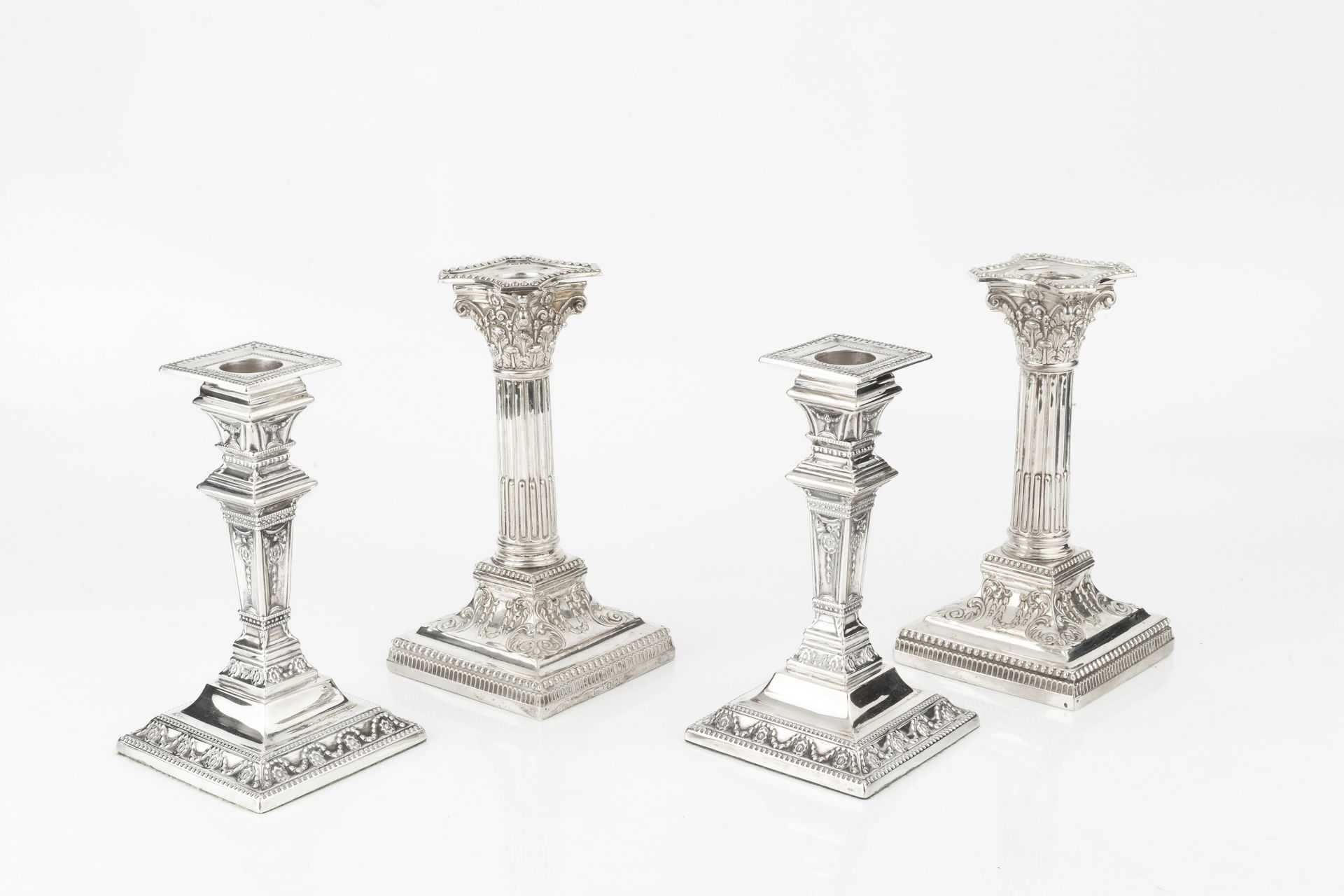 A pair of late Victorian silver candlesticks, of Corinthian form, with beaded drip trays and