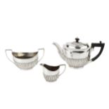 A matched silver three piece tea service, of half lobed form, the teapot with ebonised handle and