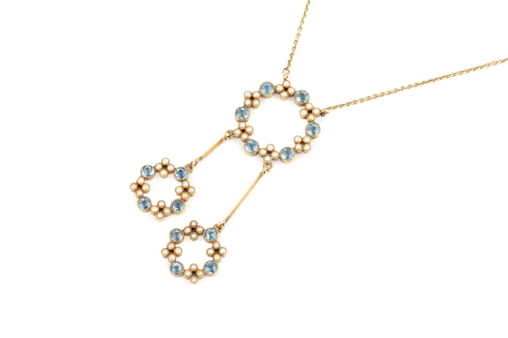 An Edwardian aquamarine and seed pearl necklace, the pendant of open circle design suspending two