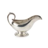 An American silver sauceboat, with shaped foliate cast border and leaf capped scroll handle, on oval
