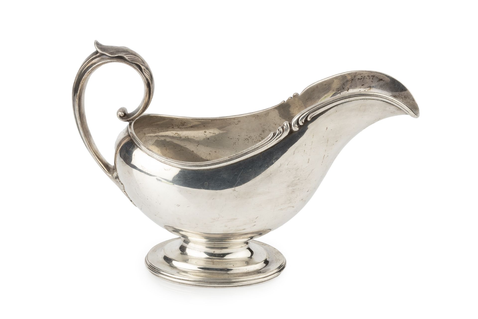 An American silver sauceboat, with shaped foliate cast border and leaf capped scroll handle, on oval