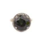 A green stone and diamond set dress ring, the circular stone, possibly moldavite, within a border of