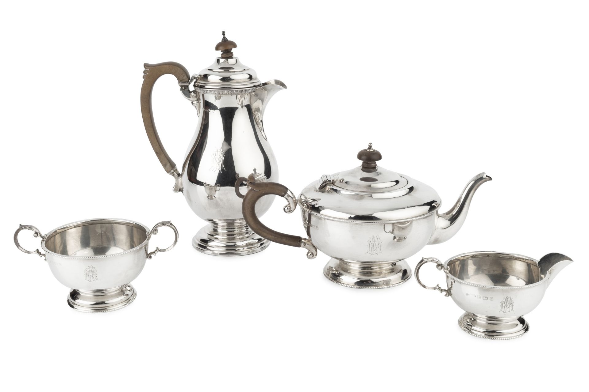 A George V silver three piece tea service, with beaded borders, the teapot with composite handle and