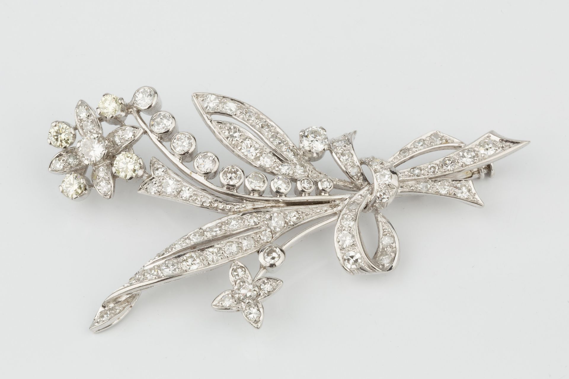 A diamond spray brooch, in the form of ribbon tied flowers and leaves, the main flower head set with - Bild 3 aus 3