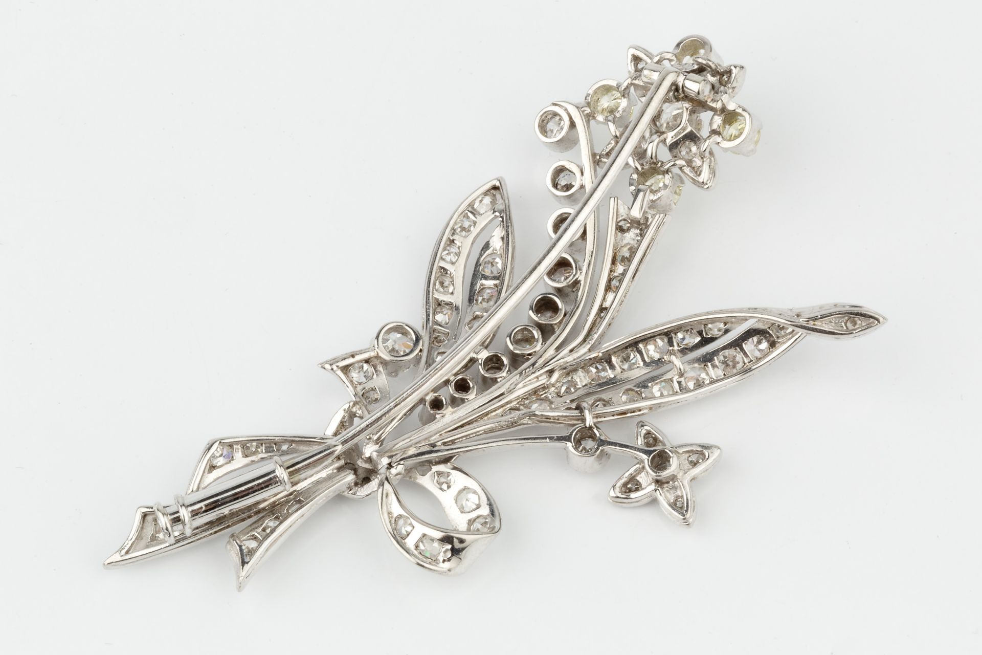 A diamond spray brooch, in the form of ribbon tied flowers and leaves, the main flower head set with - Bild 2 aus 3