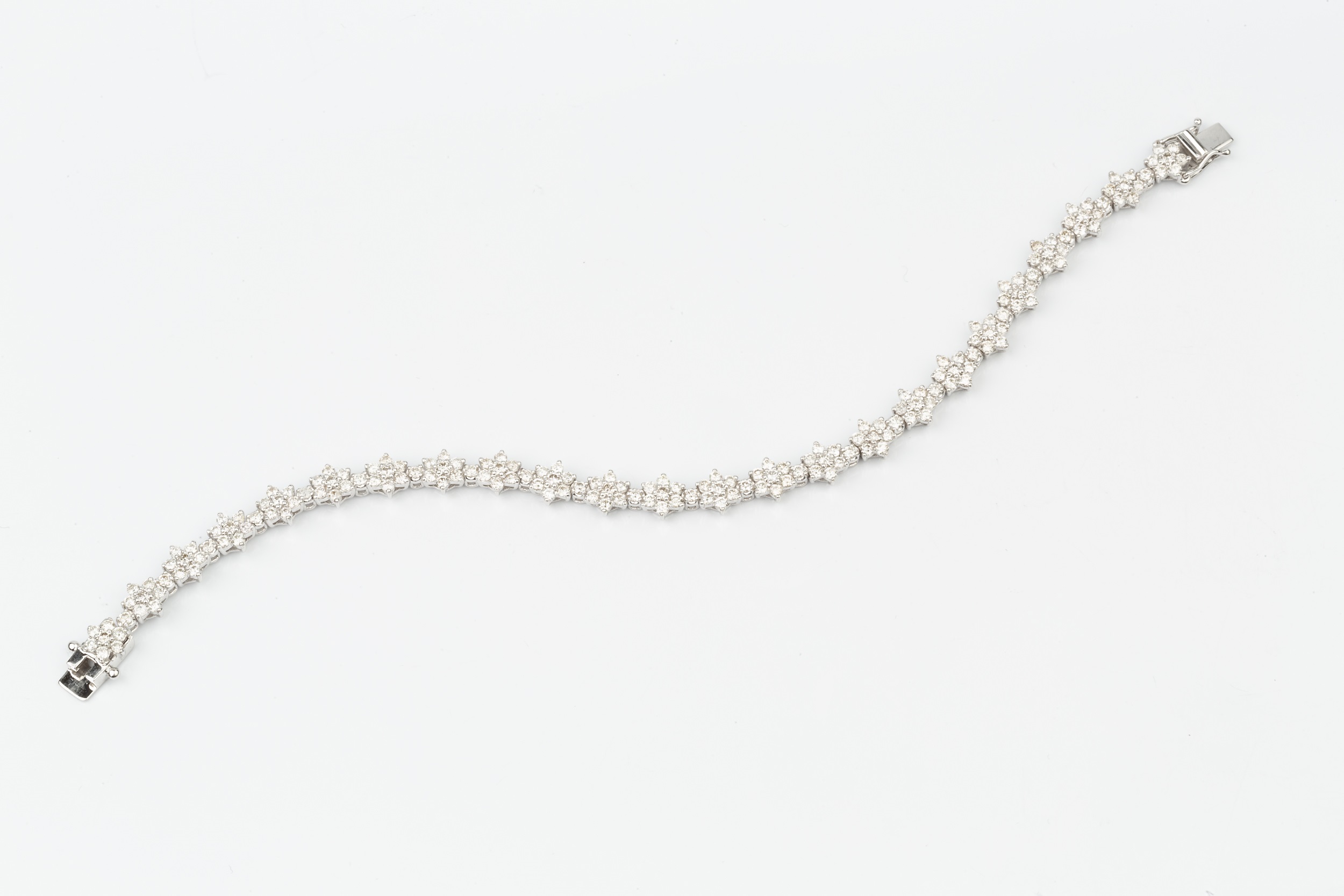 An 18ct white gold and diamond bracelet, set with a line of brilliant cut flowerhead clusters with - Image 2 of 3