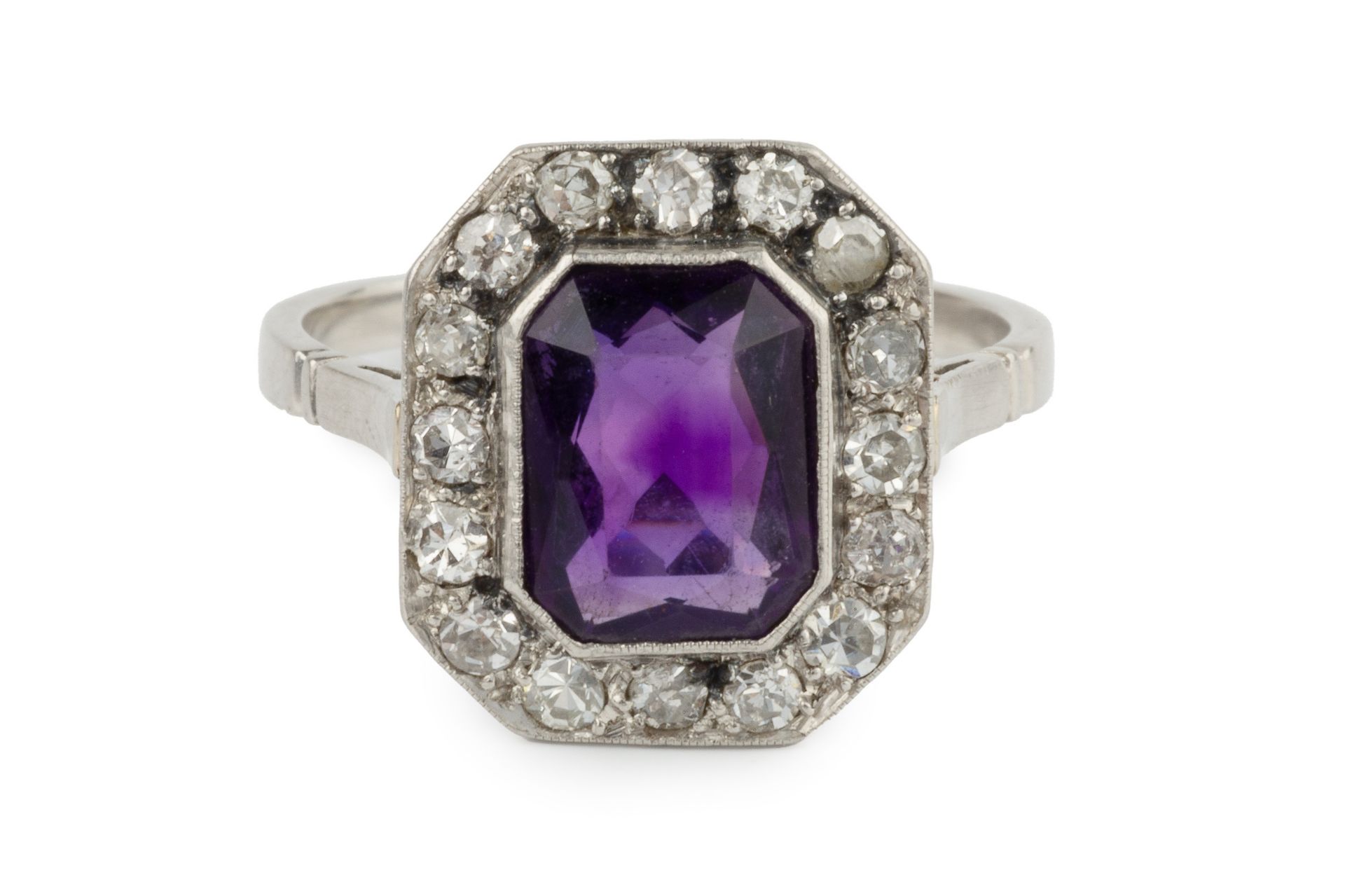 An amethyst and diamond cluster ring, the chamfered rectangular cut amethyst within a border of