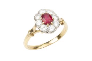 A ruby and diamond cluster ring, the oval cut ruby within a border of old brilliant cut diamonds, to