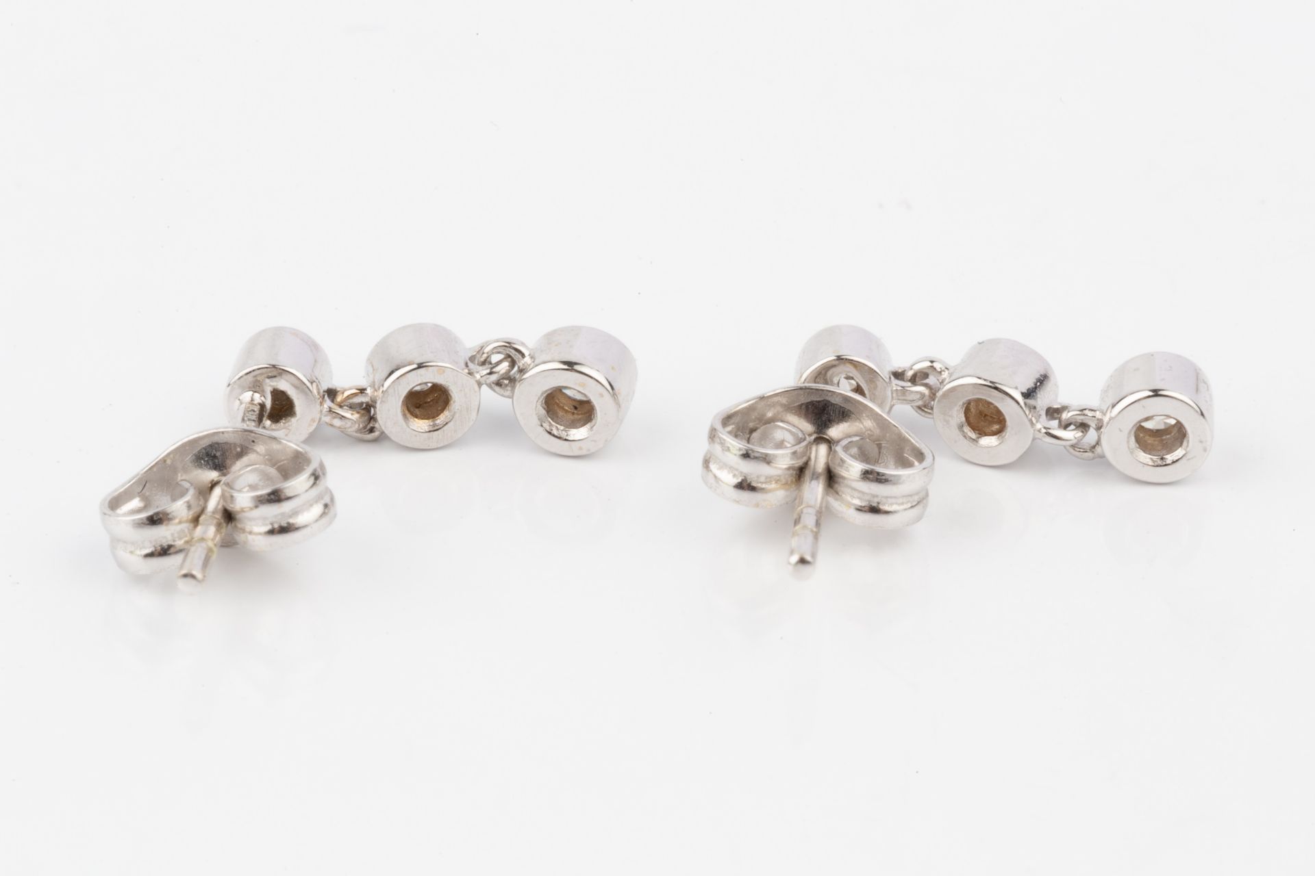 A pair of 18ct white gold and diamond earrings, each with three collet-set brilliant cut stones - Bild 4 aus 4