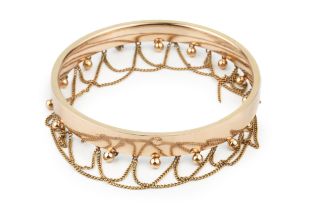 A 9ct gold circular bangle, hung to one edge with ball drops and overlapping chain festoons, 8cm