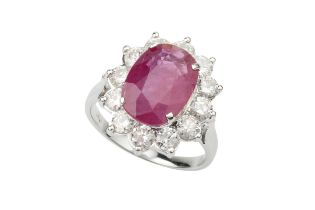 A ruby and diamond cluster ring, the oval mixed cut ruby within a border of twelve round brilliant