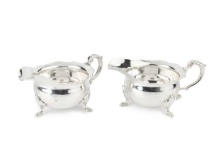 A pair silver sauce boats, of rounded circular form with shaped borders, leaf capped scroll