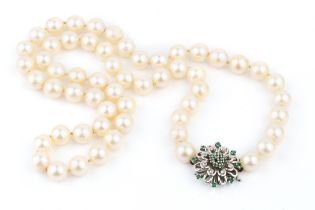 A single strand uniform cultured pearl necklace, with diamond and emerald set white precious metal