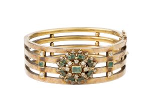 A late 19th century diamond and emerald set hinged bangle, of four bar design, centred with an
