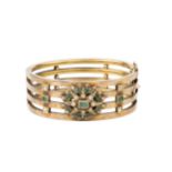 A late 19th century diamond and emerald set hinged bangle, of four bar design, centred with an