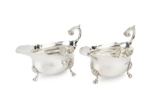 A pair of George V silver sauce boats, with shaped borders, scroll handles and shell capped pad feet