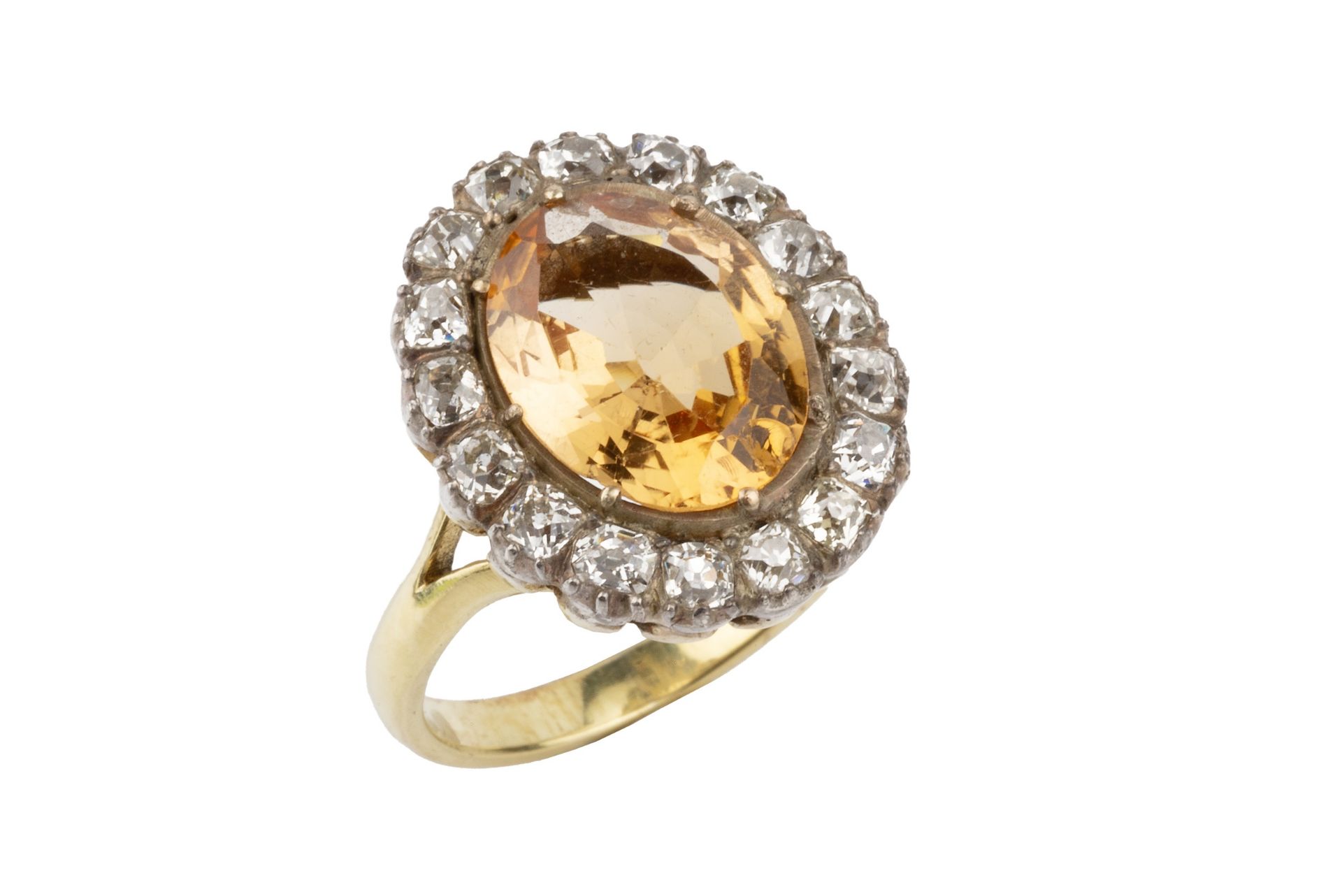 A topaz and diamond cluster ring, the oval central orange-brown topaz within a border of seventeen