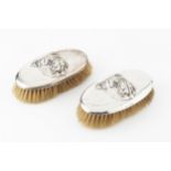 A pair of George V silver backed clothes brushes, each relief decorated with the head of a