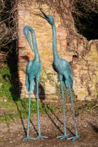 A pair of green patinated garden sculptures of storks