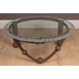 A wrought iron and frosted glass-topped crafts-made table