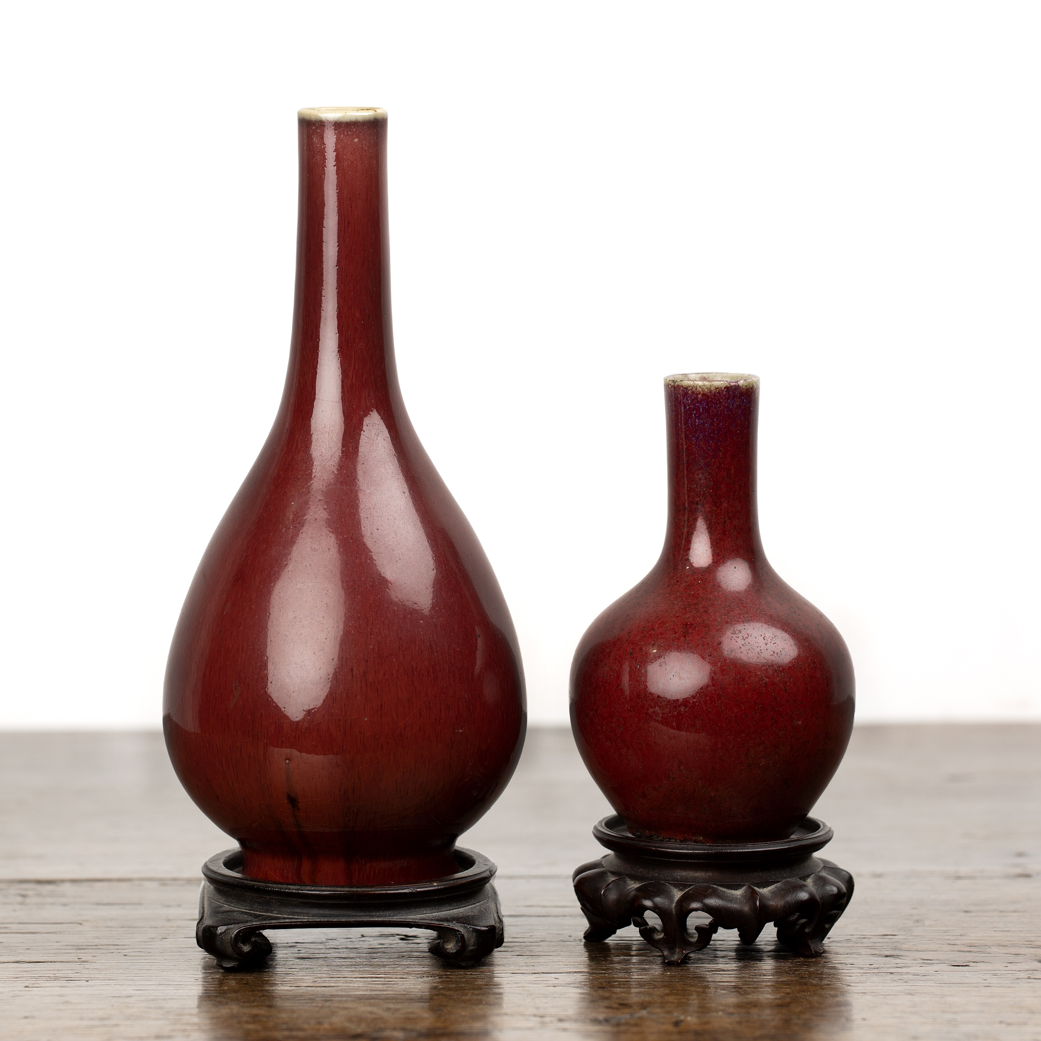 Two sang de boeuf vases on wooden stands Chinese, 18th/19th Century each of bottle vase form, 22.5cm