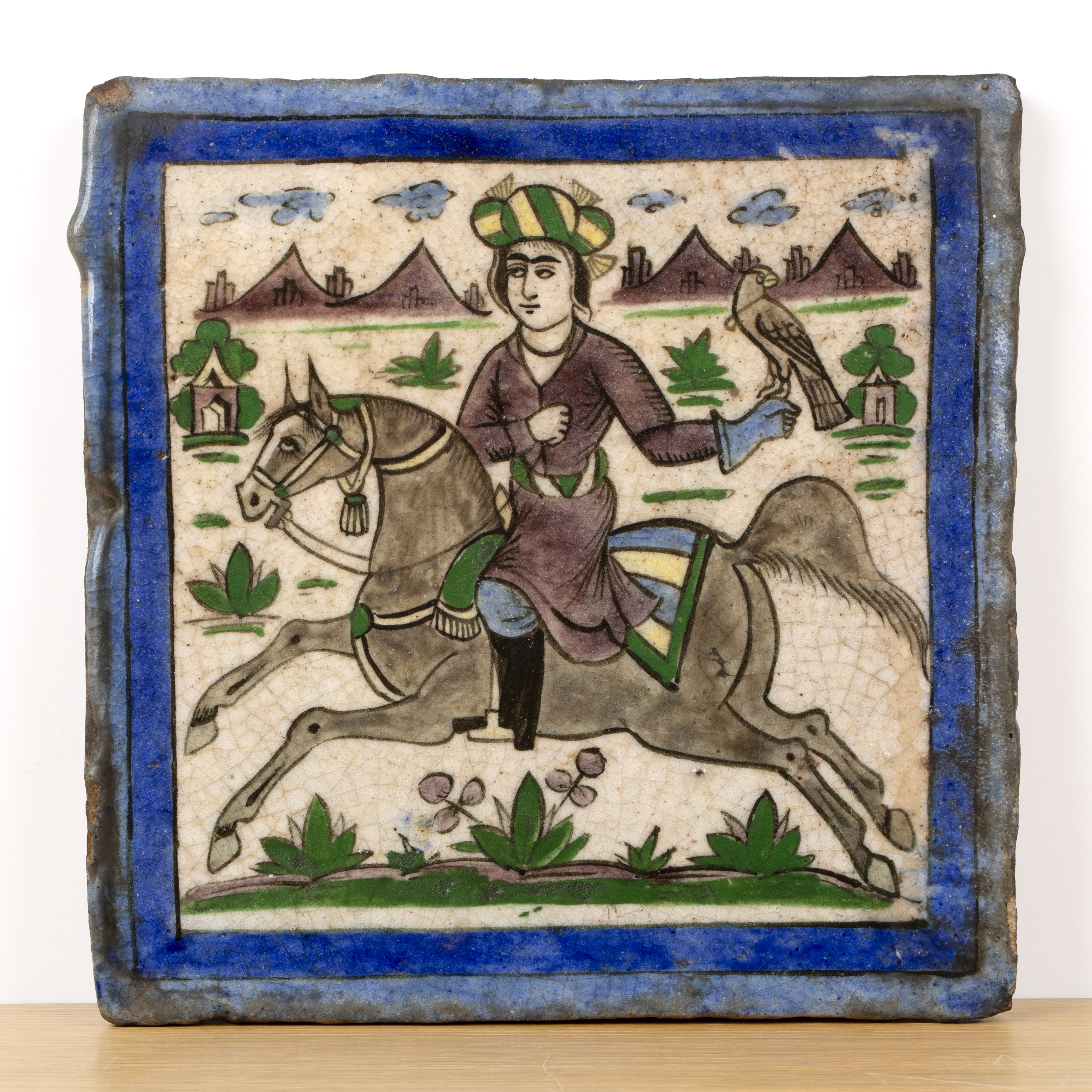 Qajar polychrome tile Iran, 19th Century with a horseback huntsman and falcon, 20.7cm square With