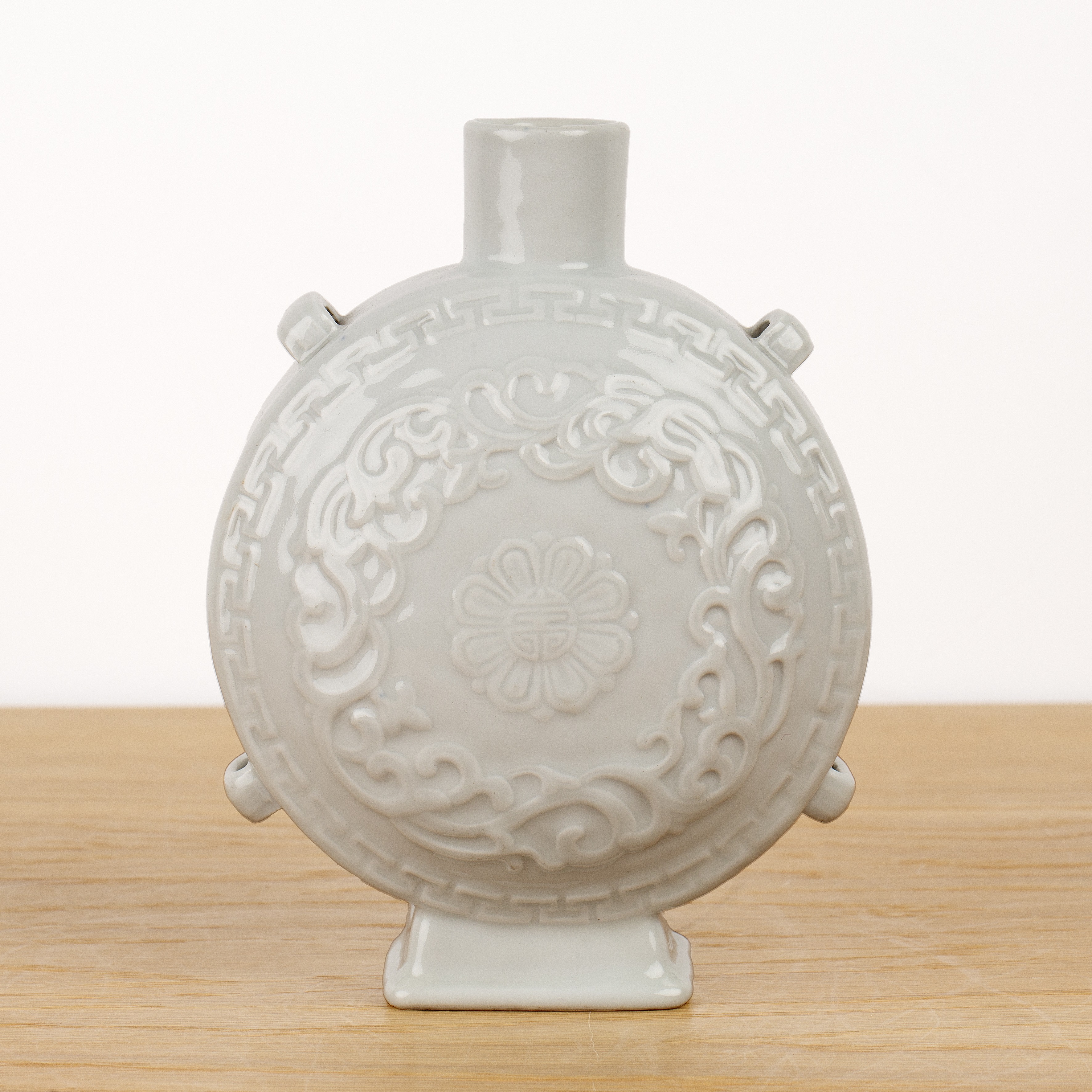 White glazed porcelain moon flask Chinese, 18th/19th Century with a central moulded flower head