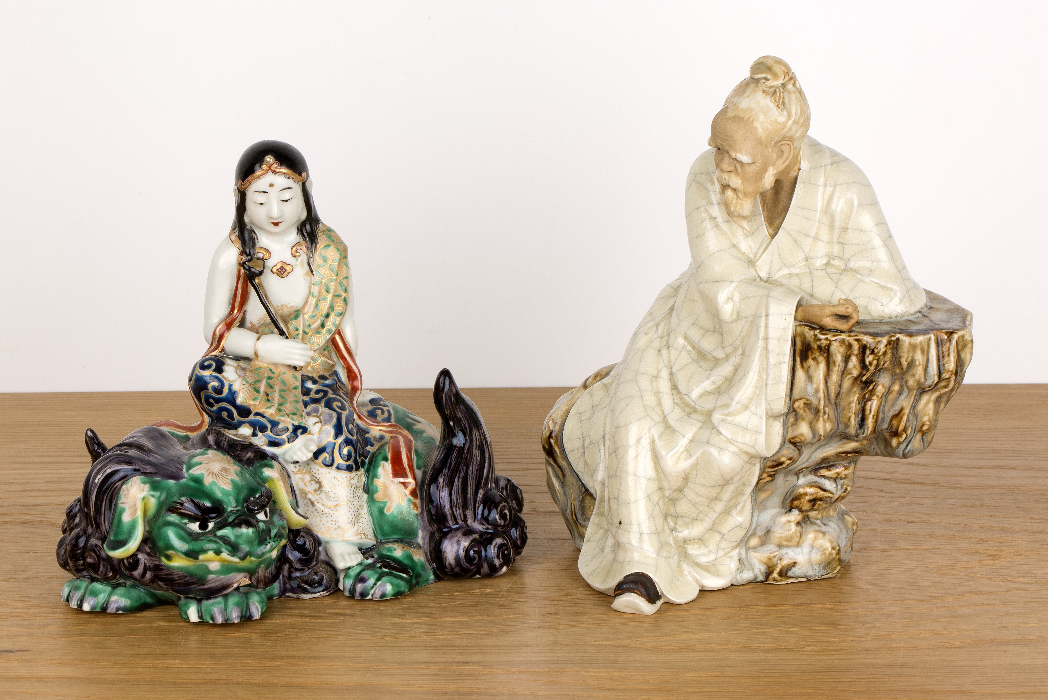 Two porcelain figures Chinese and Japanese including a seated Shiwan glazed scholar leaning