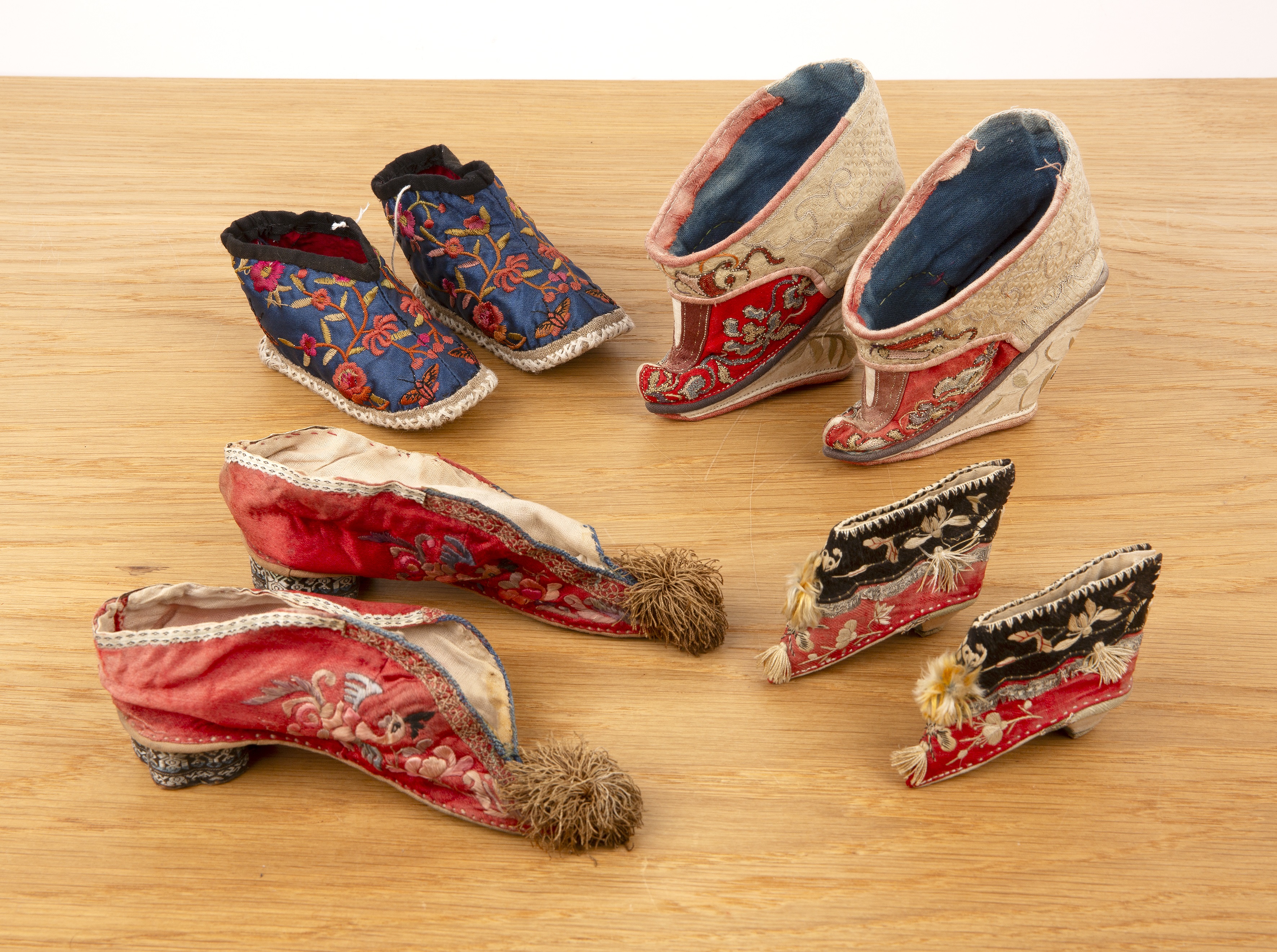 Four pairs of embroidered shoes Chinese set in three later wooden and glass cases, two cases 39.