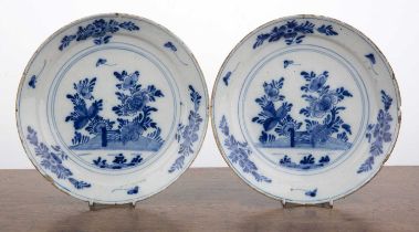 Pair of blue and white Delft plates 18th Century, each decorated with flowers, a hill and a gate