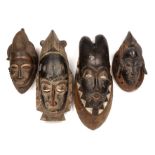 A group of four Baule masks, Ivory coast, the largest 18cm wide 45cm high. Losses to the ends of the