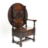 An early 20th century oak monks seat, the lifting back with a carved floral design all raised on