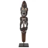 An antique Sepik river flute stopper, with cowrie eyes and painted decoration 42cm high