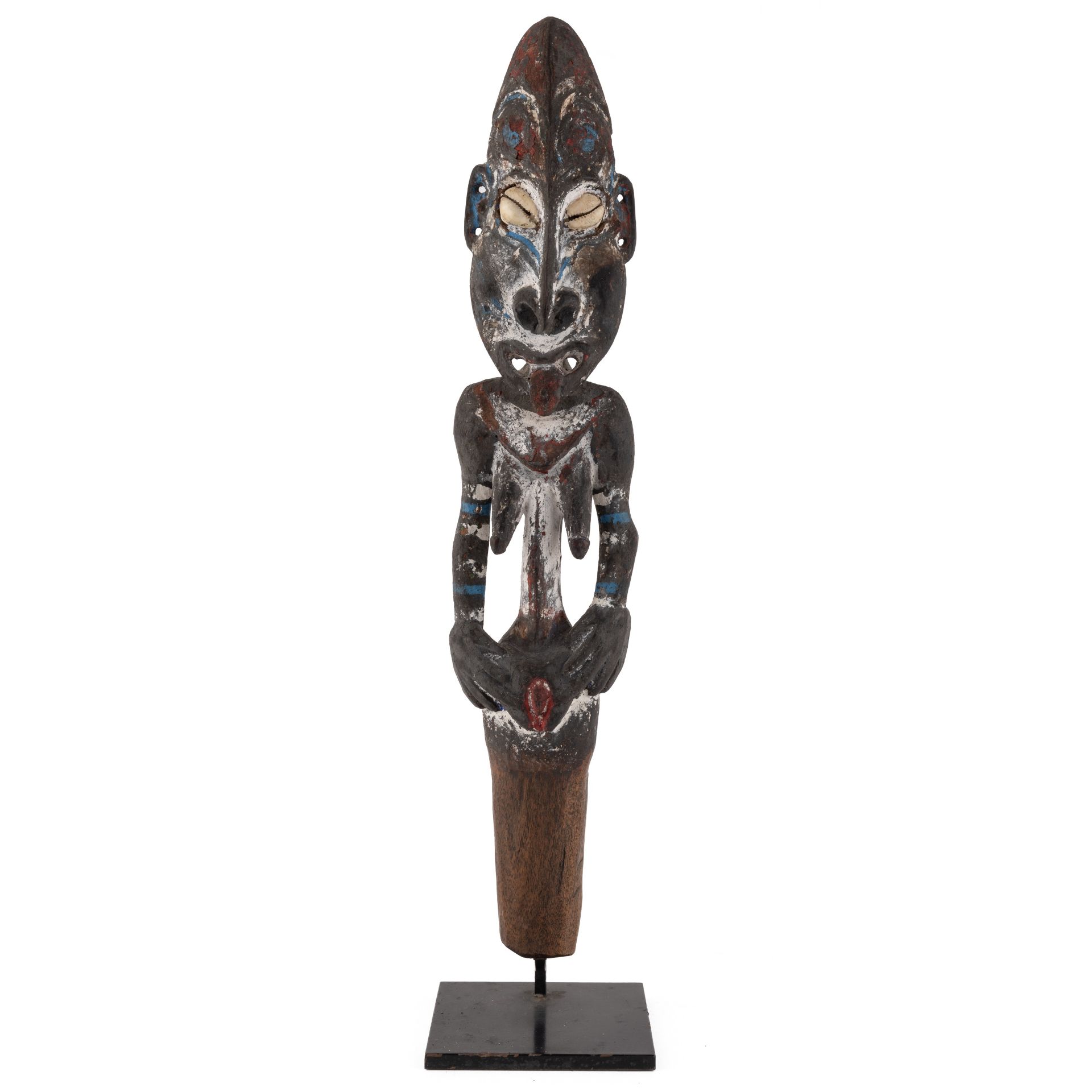 An antique Sepik river flute stopper, with cowrie eyes and painted decoration 42cm high
