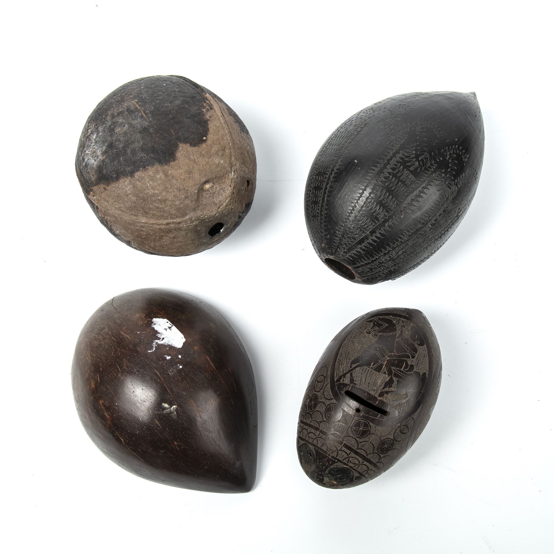 Four antique tribal nuts, two with engraved decoration, the largest 14cm high