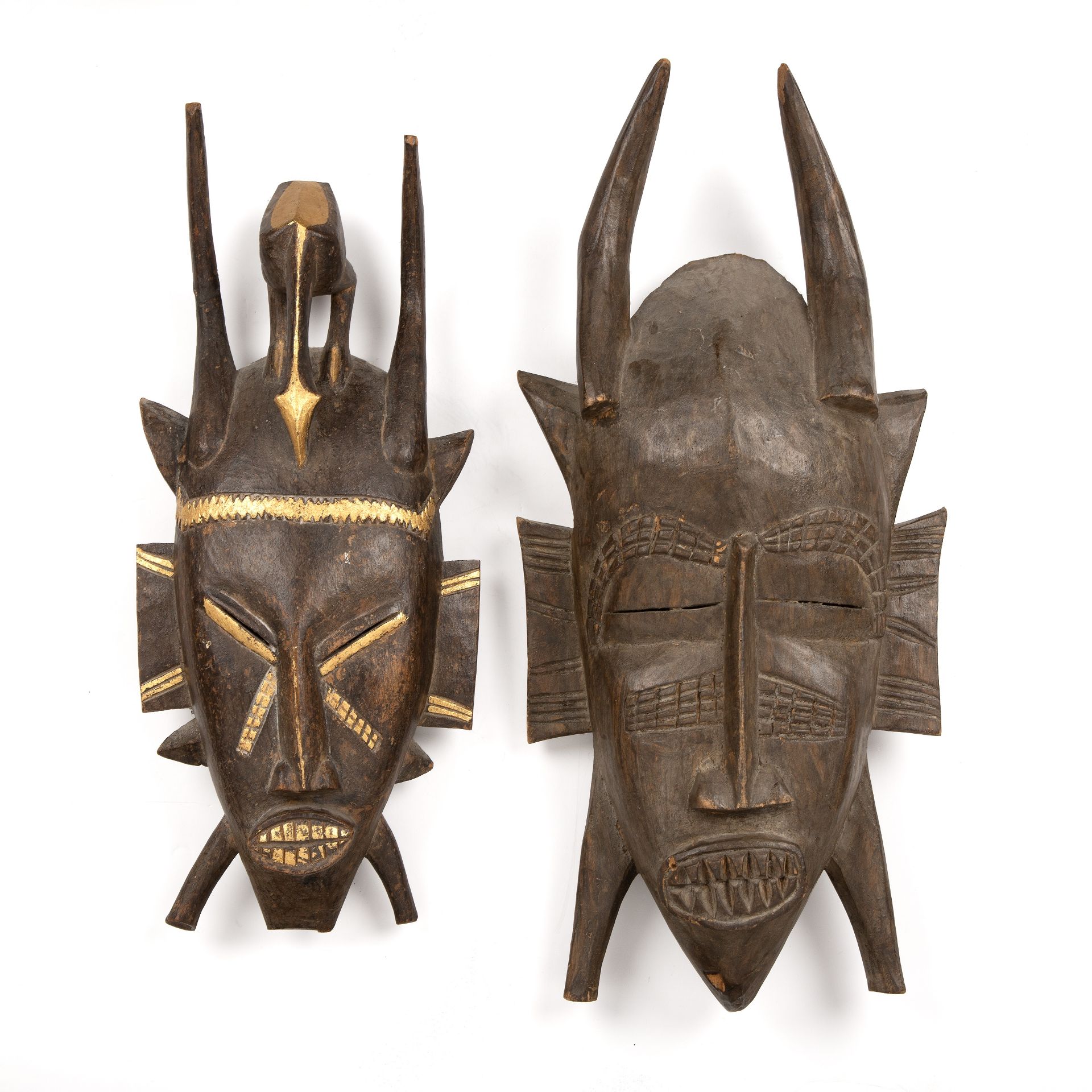 Two carved hardwood African masks, one with gilded decoration, the largest 29cm x 60cm