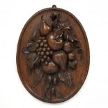 An 18th/19th century carved oak oval panel depicting a still life of fruit 37cm x 47cm