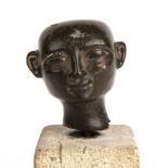 An antique eastern hardstone head 5cm x 5cm mounted on a stone plinth.