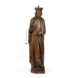 A early 19th century carved oak figure of a priest 16cm wide 65cm high. Corner missing to the