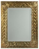 An arts and crafts pressed brass framed wall mirror with bevelled glass 38.5cm x 49cm